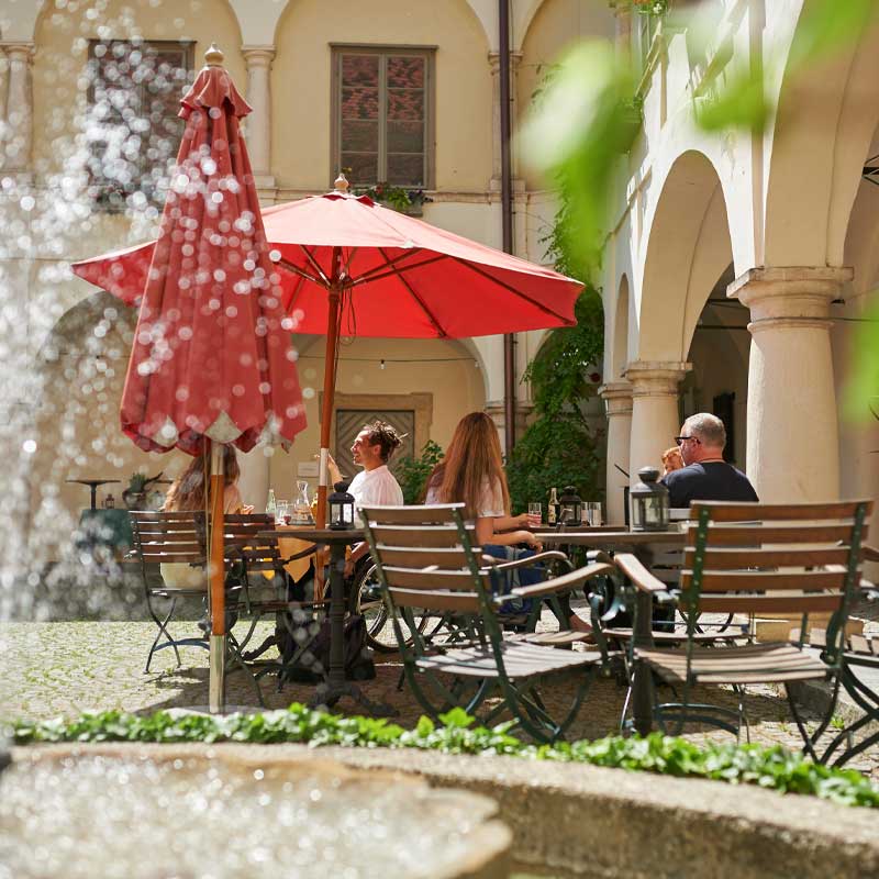 Der Innenhof mit Tischen und Stühlen vor einem Brunnen